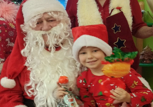 chłopiec z prezentem siedzi na kolanach Mikołaja