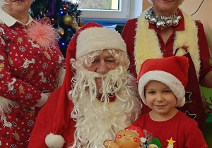 chłopiec z prezentem siedzi na kolanach Mikołaja