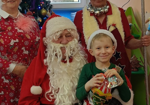 chłopiec z prezentem siedzi na kolanach Mikołaja