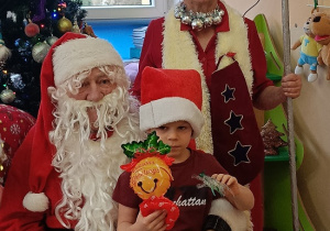 chłopiec z prezentem siedzi na kolanach Mikołaja