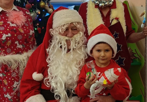 chłopiec z prezentem siedzi na kolanach Mikołaja