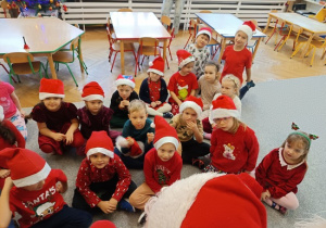 dzieci w czapkach mikołajkowych siedzą na wykładzinie