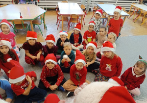 dzieci w czapkach mikołajkowych siedzą na wykładzinie