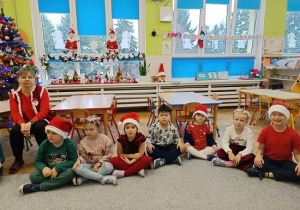 dzieci w czapkach mikołajkowych siedzą na wykładzinie