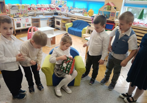 dzieci stoją w półkolu i składają życzenia jubilatce