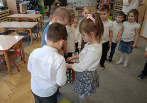 dzieci stoją w półkolu i składają życzenia jubilatce