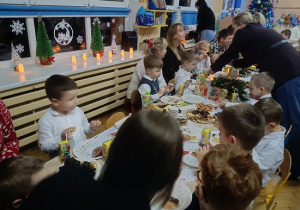 dzieci i rodzice siedzą przy stolikach i jedzą słodkości