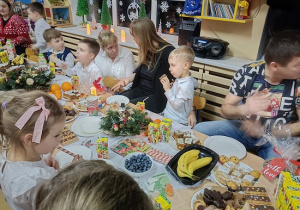 dzieci i rodzice siedzą przy stolikach i jedzą słodkości