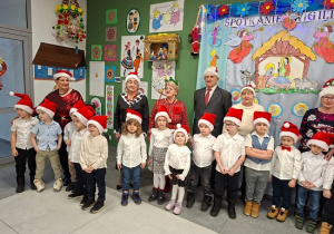 dzieci w czapkach mikołajkowych śpiewają kolędy