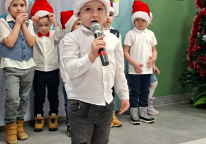 chłopiec w czapce Mikołaja prezentuje wiersz