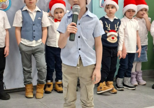 chłopiec w czapce Mikołaja prezentuje wiersz