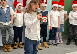 chłopiec w czapce Mikołaja prezentuje wiersz