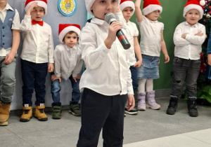 chłopiec w czapce Mikołaja prezentuje wiersz