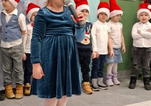 dziewczynka w czapce Mikołaja prezentuje wiersz