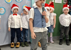 chłopiec w czapce Mikołaja prezentuje wiersz