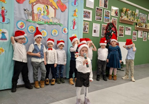 diewczynka w czapce Mikołaja prezentuje wiersz