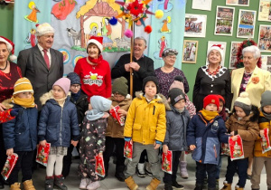 dzieci z prezentami i seniorami pozują do zdjęcia