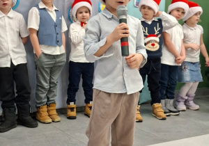 chłopiec w czapce Mikołaja prezentuje wiersz