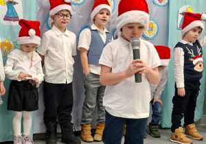 chłopiec w czapce Mikołaja prezentuje wiersz