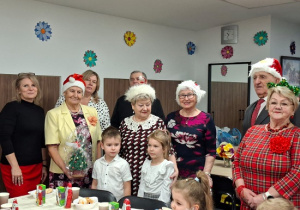 dzieci wręczają prezent choinkę seniorom