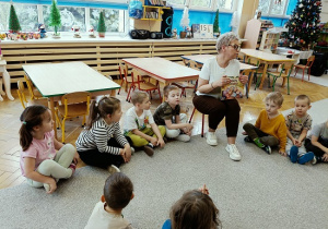 dzieci siedzą w półkolu i słuchają czytanej przez Panią książki