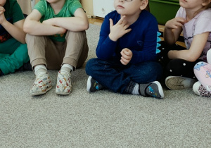 chłopcy siedzą przy szafkach i słuchają Pani