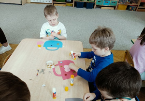 dzieci wykonują papierowe torebki i naklejają naklejki