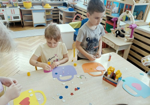 dzieci wykonują papierowe torebki i naklejają naklejki