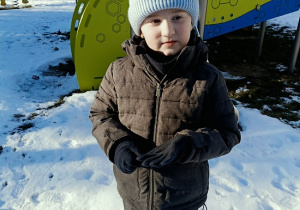 chłopiec stoi obok zjeżdżalni w śniegu