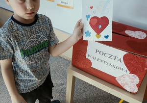 chłopiec wrzuca do papierowej skrzynki swoją walentynkę