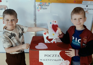 chłopcy wrzucają do skrzynki papierowe walentynki