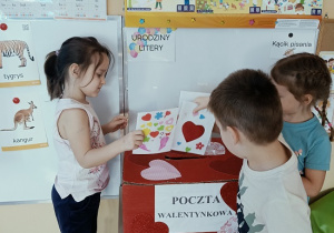 dzieci wrzucają do skrzynki papierowe walentynki