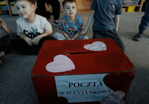 dzieci siedzą wokół skrzynki z walentynkami