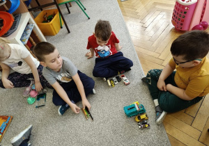 chłopcy siedzą na wykładzinie i przeliczają zabawki