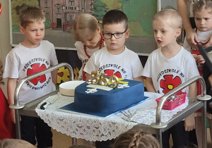 dzieci zdmuchują świeczki na torcie