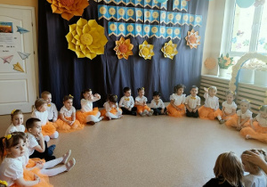 dzieci w odświętnych strojach siedzą w kręgu