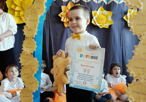 chłopiec z dyplomem i maskotką pozuje do zdjęcia