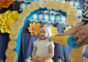 dziewczynka z dyplomem i maskotką pozuje do zdjęcia