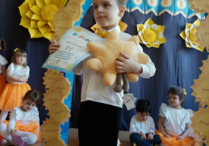 chłopiec z dyplomem i maskotką pozuje do zdjęcia