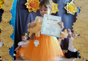 dziewczynka z dyplomem i maskotką pozuje do zdjęcia