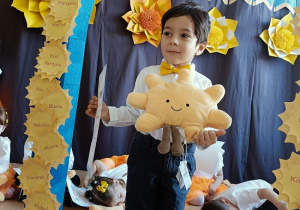 chłopiec z dyplomem i maskotką pozuje do zdjęcia