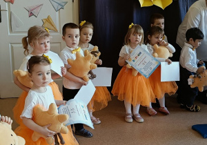 dzieci pozują do zdjęcia z dyplomami i maskotkami