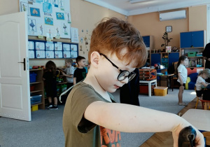 chłopiec sadzi cebulę do pojemniczka z ziemią