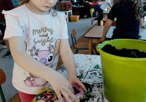 dziewczynka sadzi cebulę do pojemniczka z ziemią