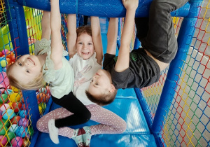 dzieci podczas zabawy w kulkach zwisają na drążku