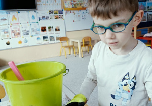 chłopiec sieje owies w doniczce