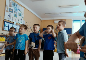 chłopcy w niebieskich koszulkach stoją w półkolu