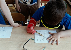 dziecko w goglach i rękawicy koloruje rysunek