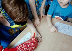 dziecko w goglach i rękawicy koloruje rysunek