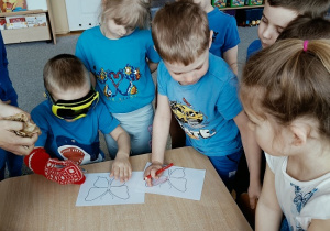 dziecko w goglach i rękawicy koloruje rysunek inne dzieci obserwują